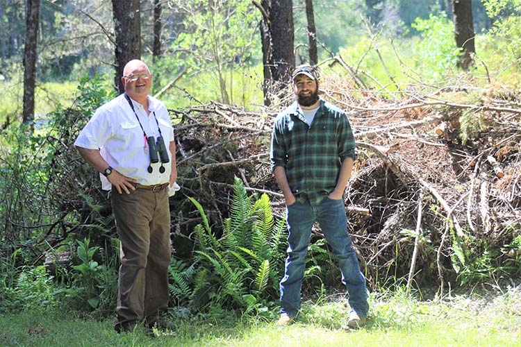 Mark stands with Frank Curtin, NRCS Soil Conservationist, with wetland habitat in the background.