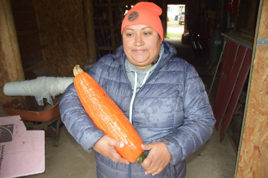 Rosebud Schneider holds a large, orange squash.