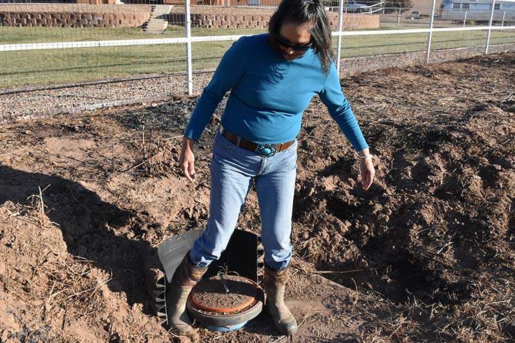 Tolani kicks dirt off a new irrigation valve.