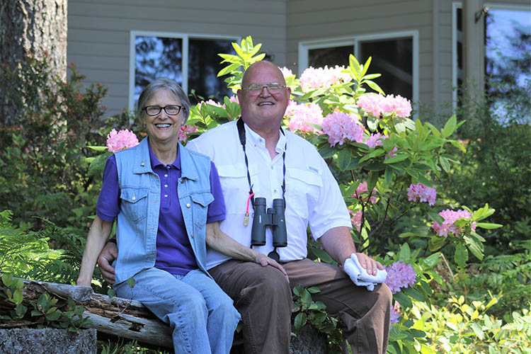 Mark and Beth Biser sit on a log bench, owners of Still Waters Farm in Mason County, Washington, sit on a bench in front of their farm.