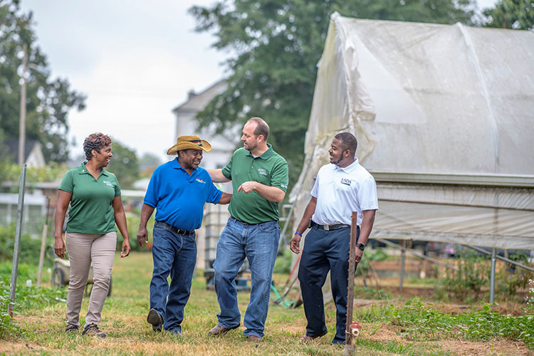 Chris discusses USDA programs for veterans with Georgia farmer Bobby Wilson while walking on Wilson's farm.