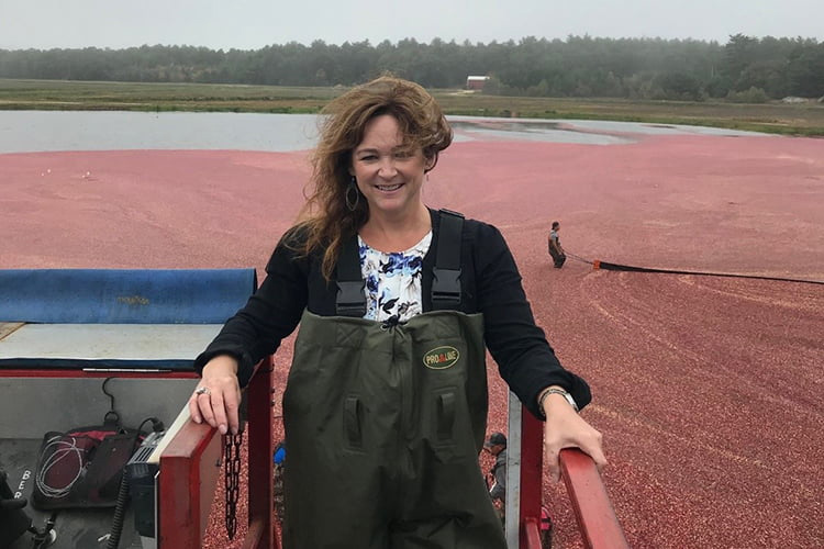 Peggy Browne stands in front of d a cranberry bog in Massachusetts.