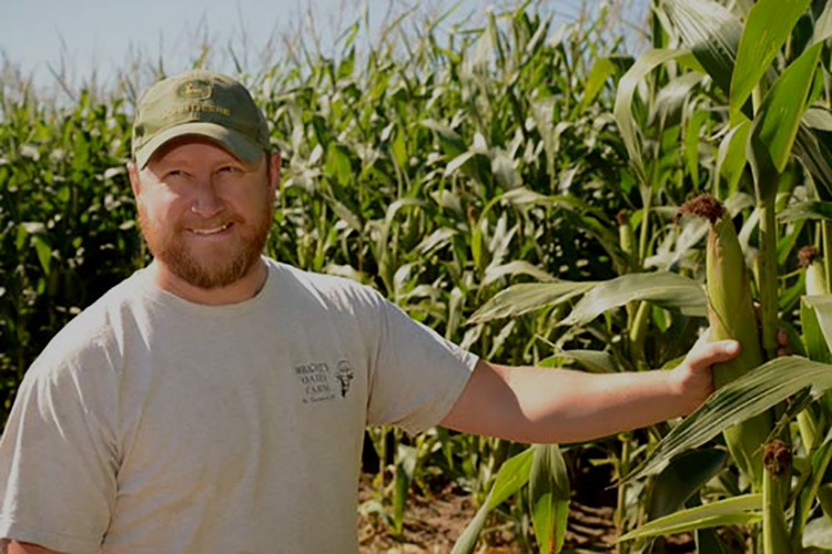 Clayton, standing in his corn field, is a fourth-generation dairy farmer. 