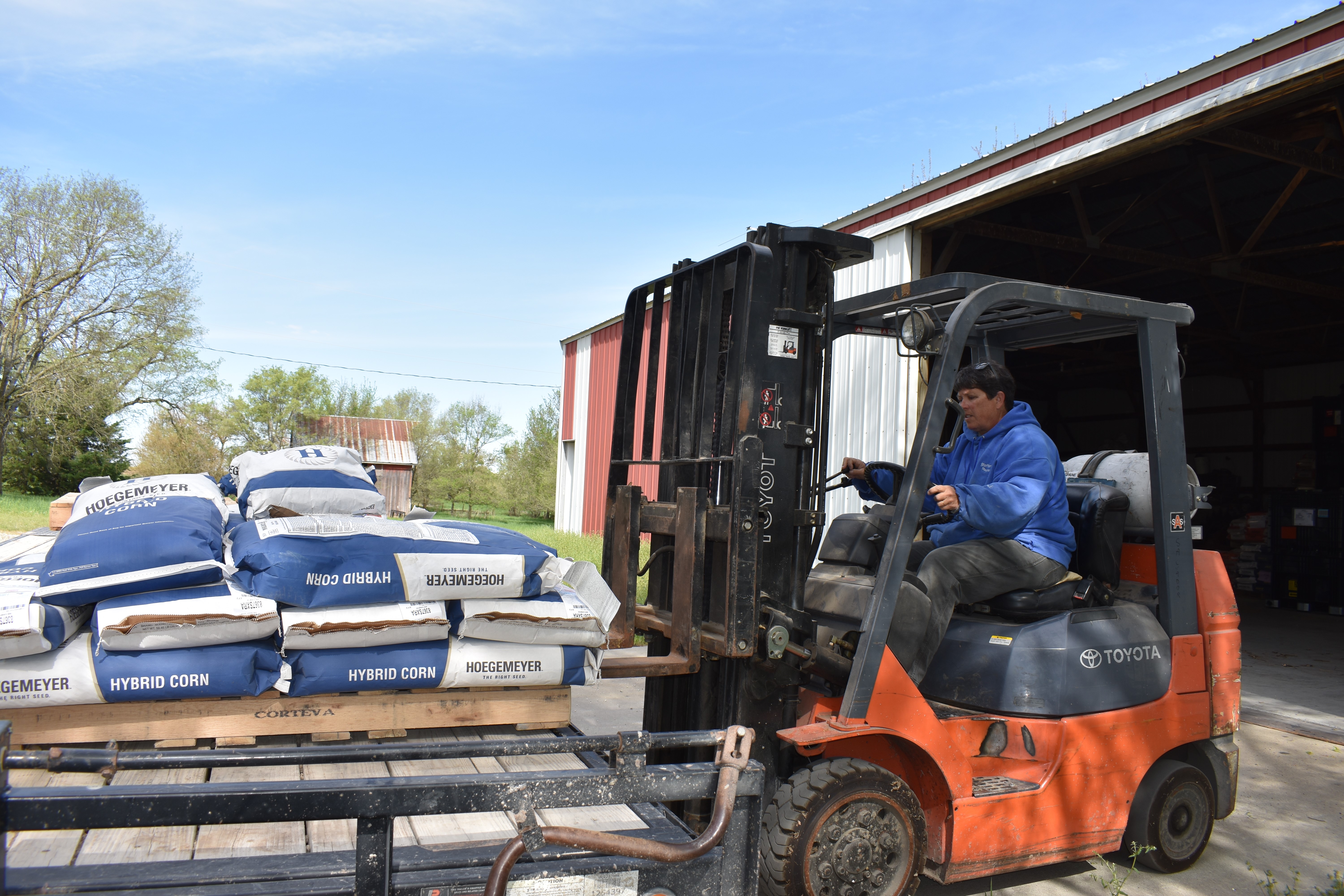 Paula Sue Steffen is driving a fork lift which is lifting multiple bags of soil