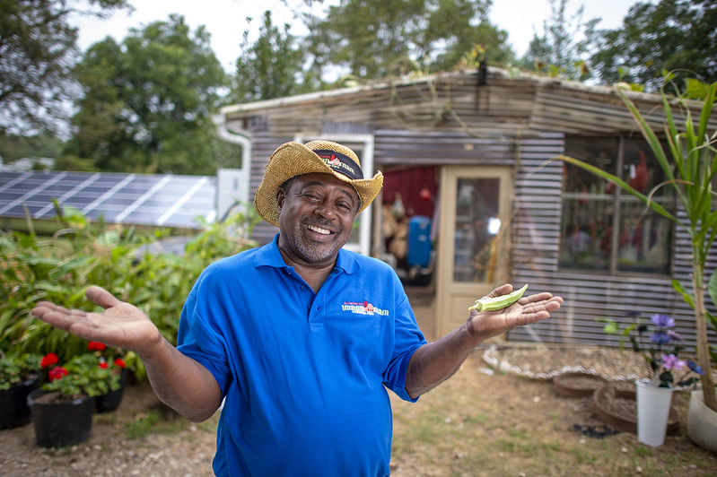 Bobby Wilson stands with arms open on aisle of his farm