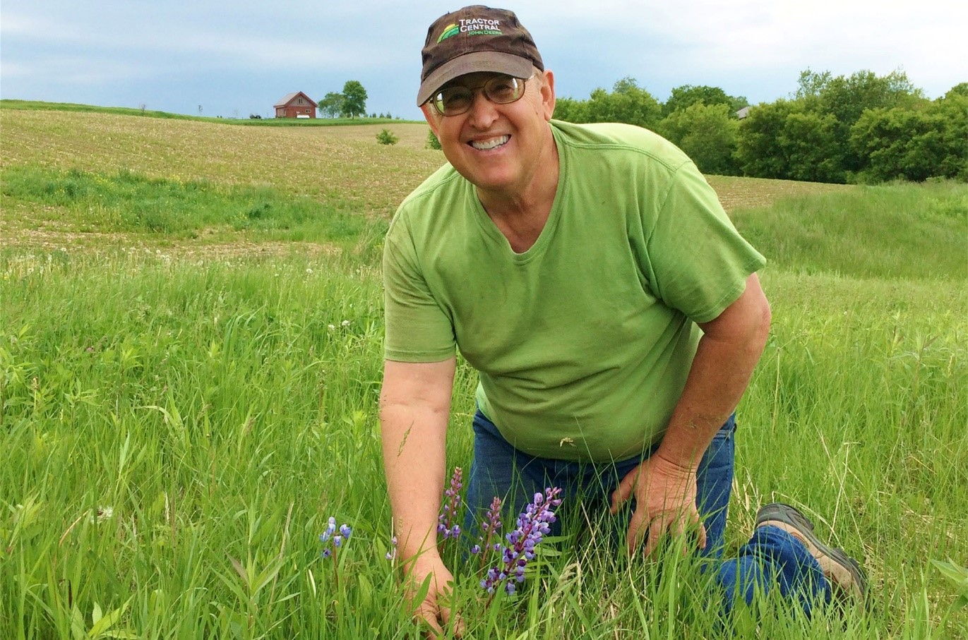 Dale Bigler kneeling in field smiling into camera
