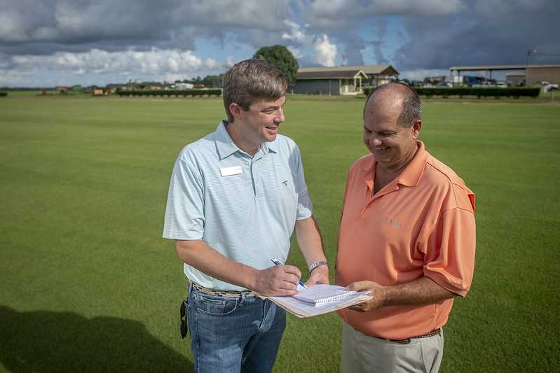 Matthew Wilkin talks with unnamed person in field