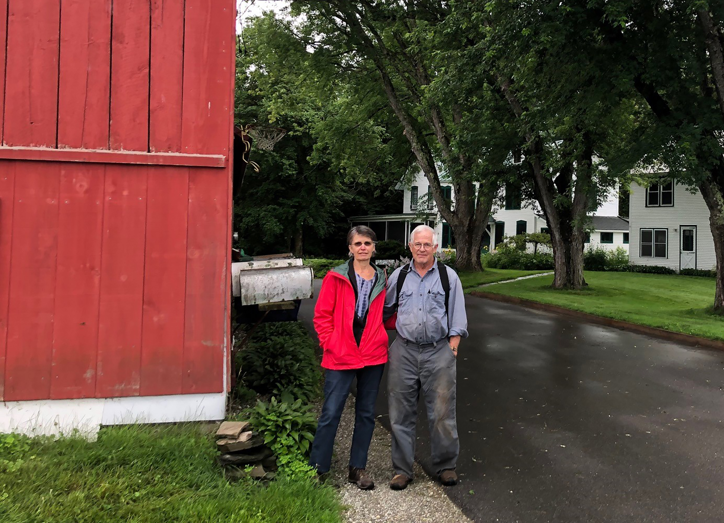 Two people standing next to red barn