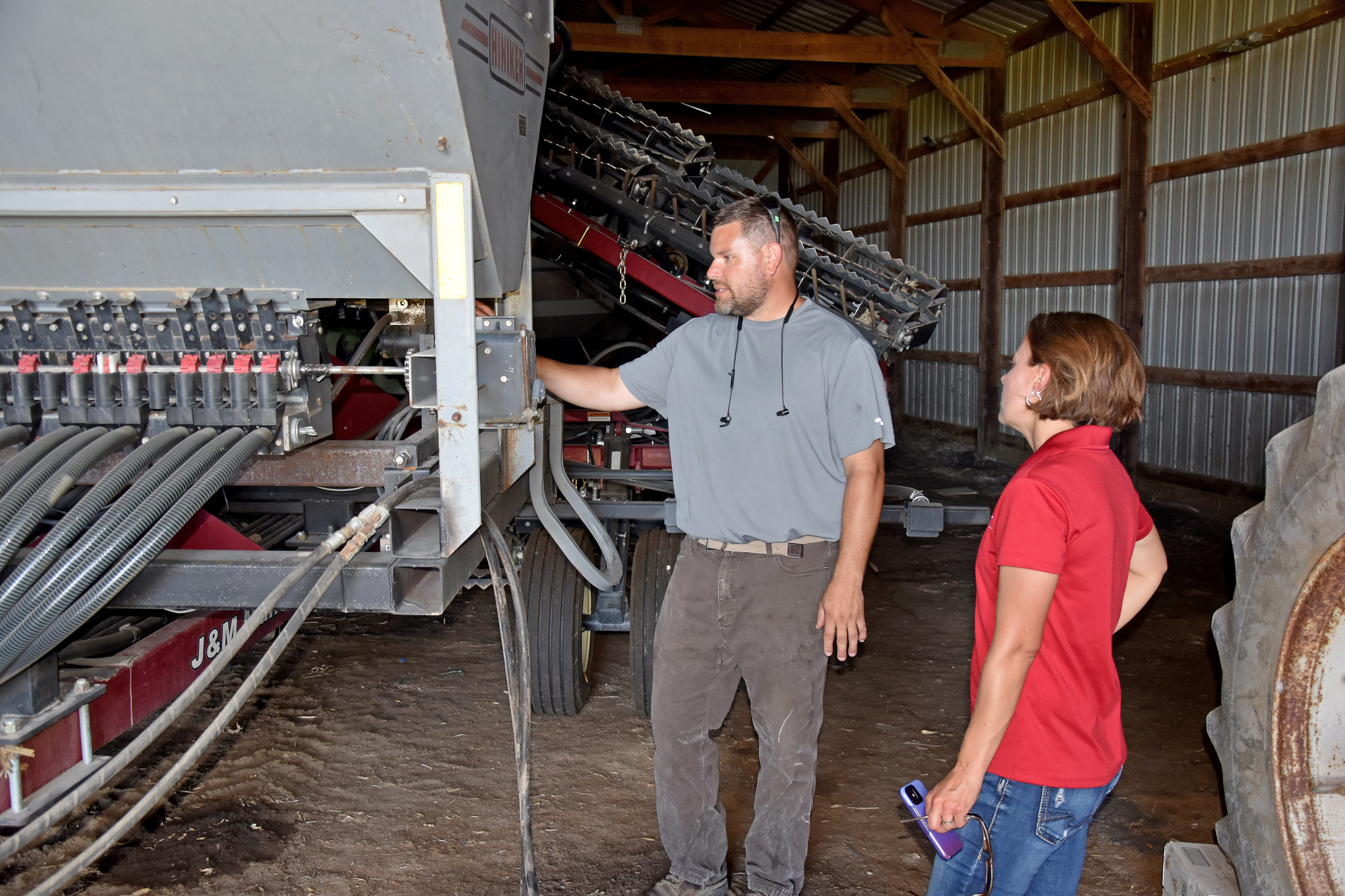 Two people operating equipment in barn