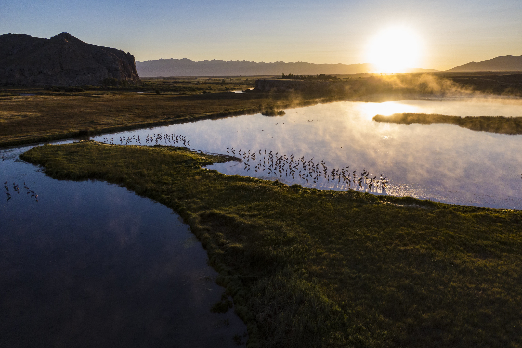 River running through grassy land with hills in background