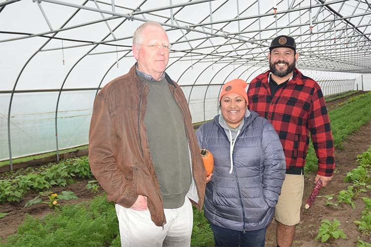 Three people standing in greenhouse