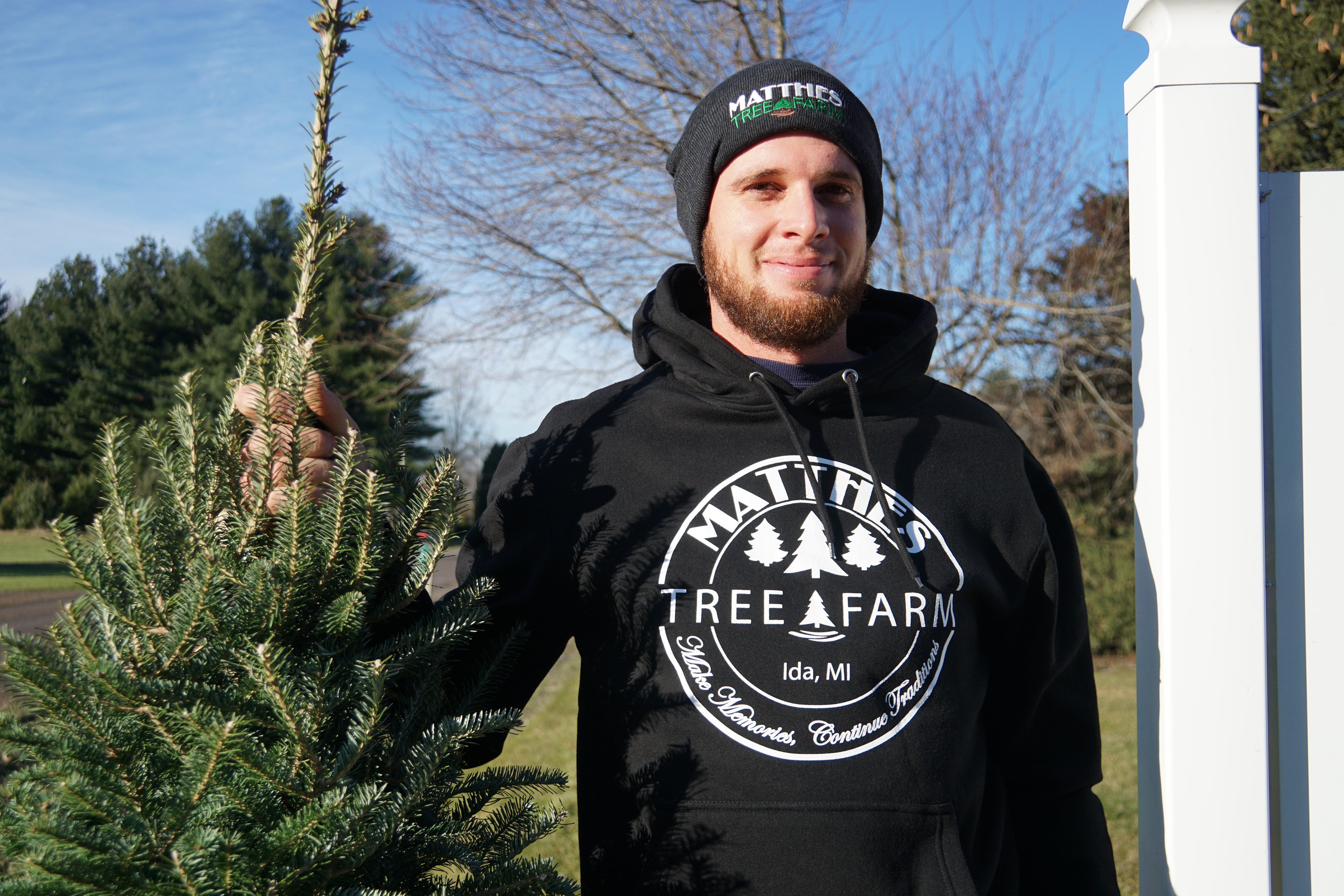 Person stands holding small tree upright