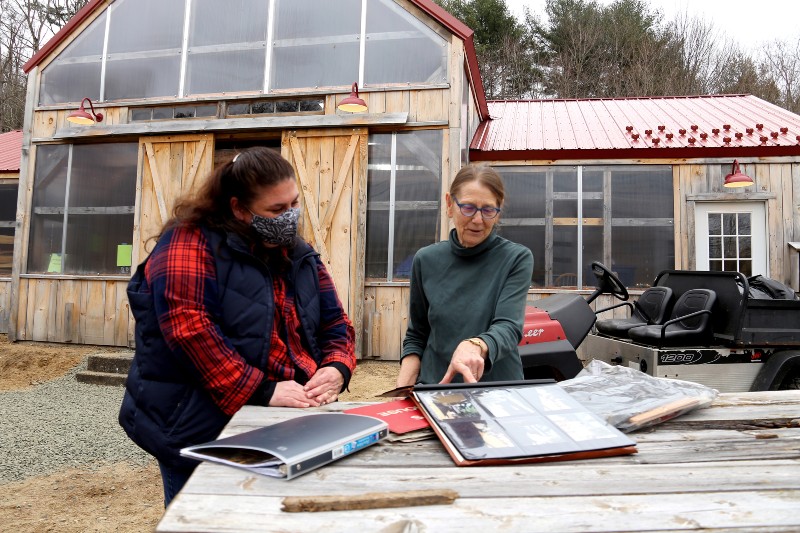 Two women standing outside looking at a photo album. 