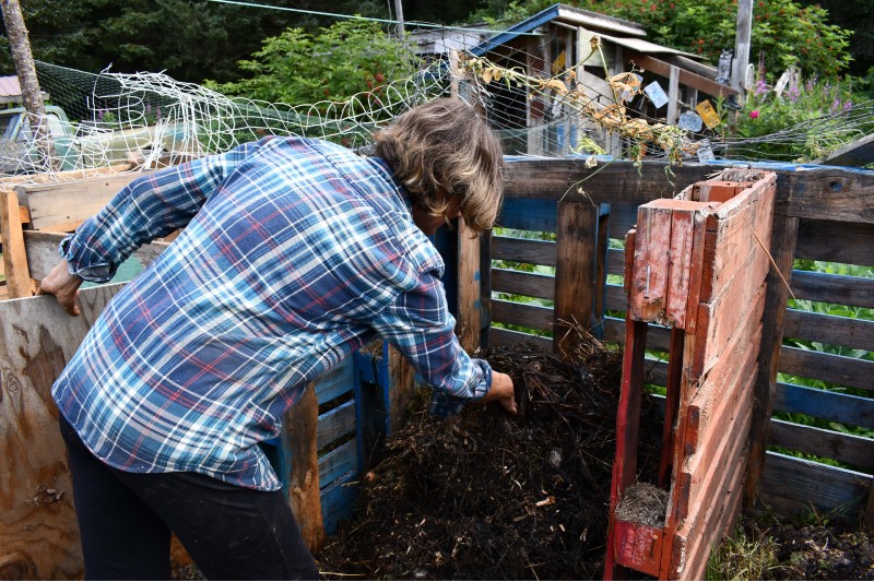 Woman handling compost in a compost bin. 