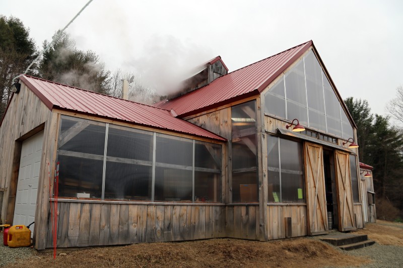 A wood frame building with smoke coming out of the top. 