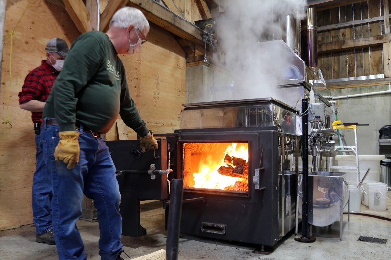 Two men looking at a wood burning oven. 