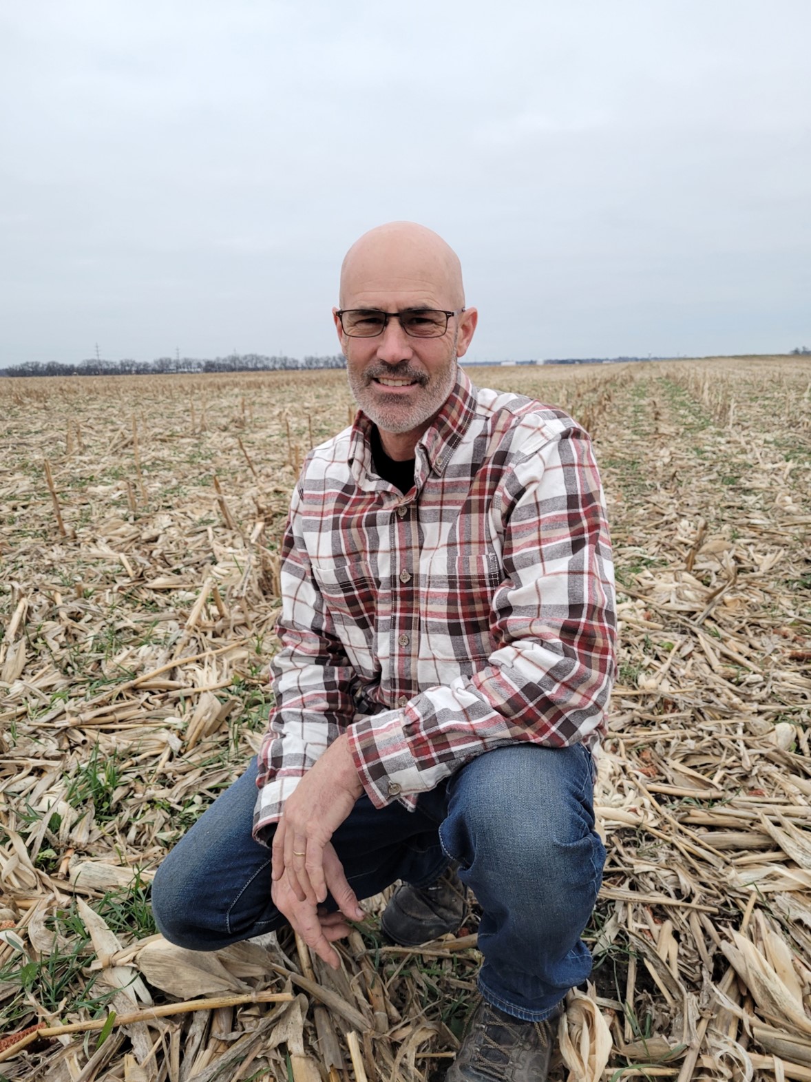 Man squating in field of cover crops