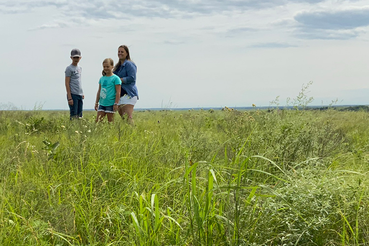 Three people standing in grassland