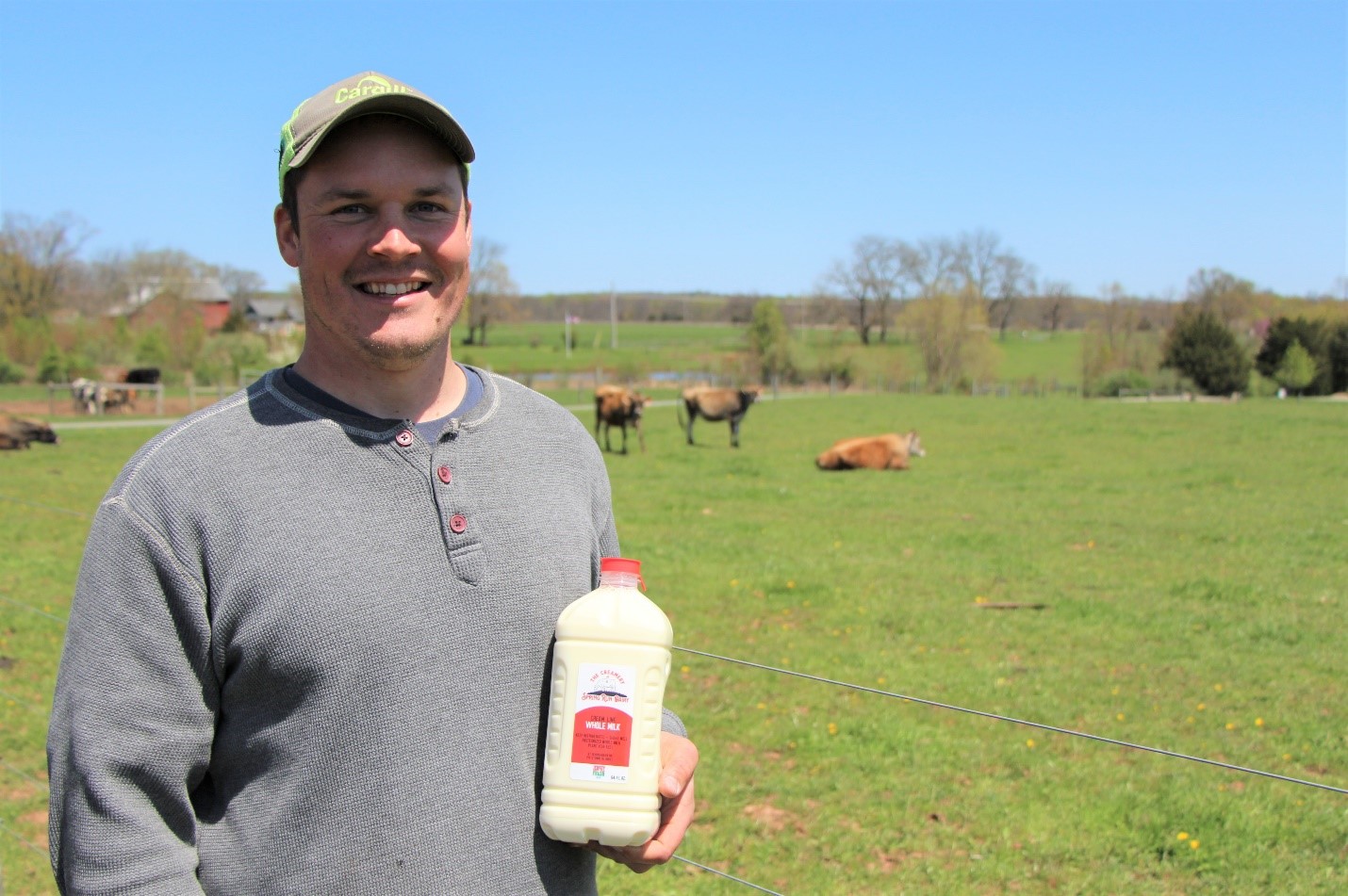 Man holding milk carton while standing in pasture
