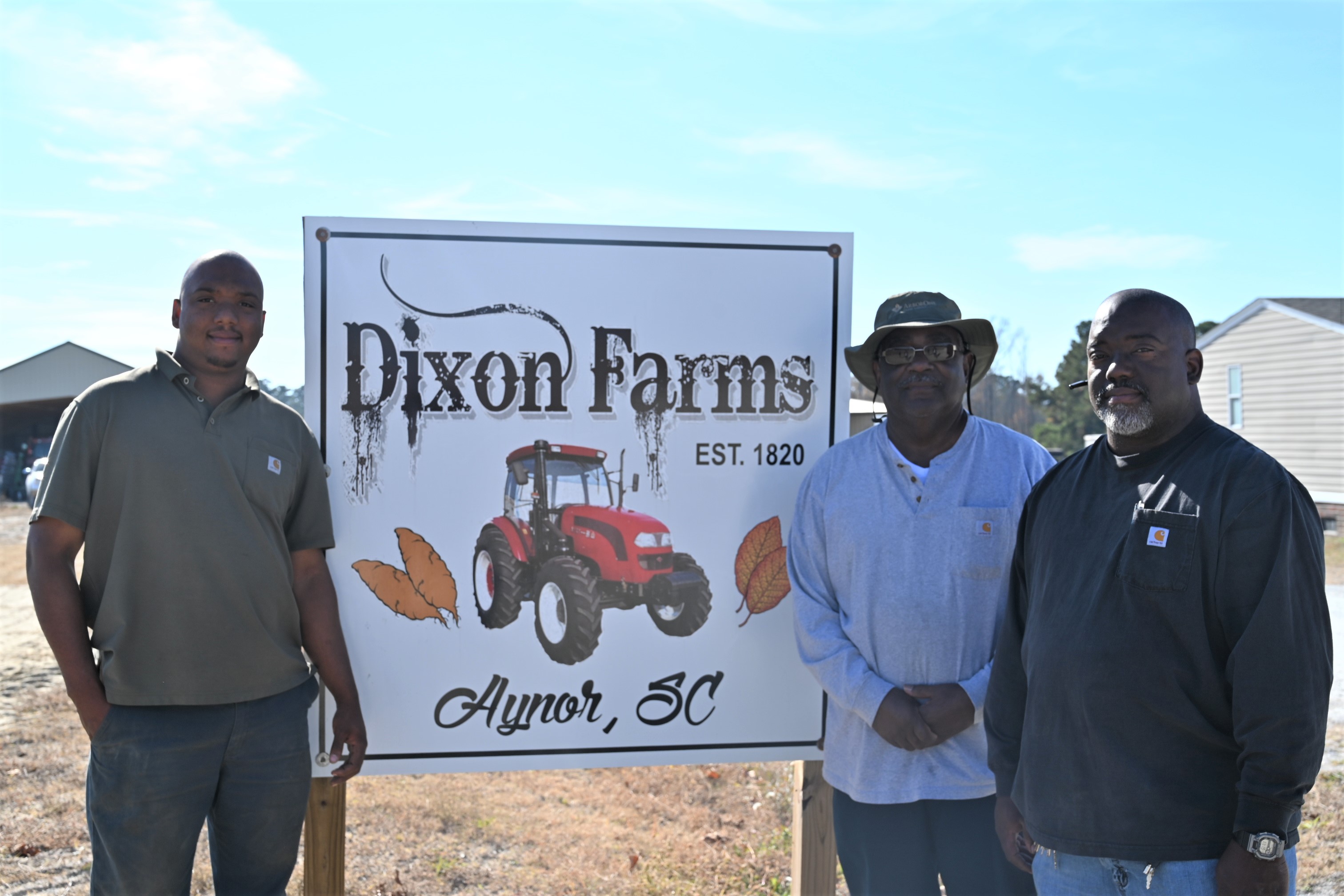 People standing next to Dixon Farms sign