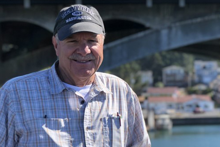 Person posing in front of bridge