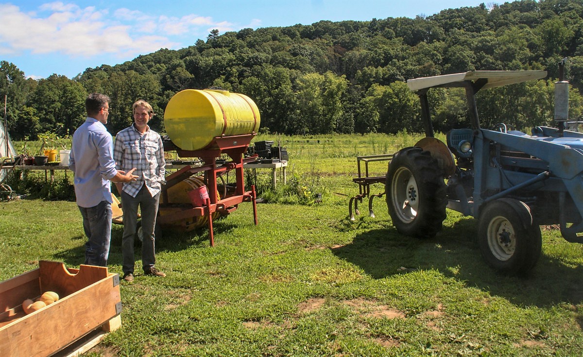 Two people talking next to blue tractor