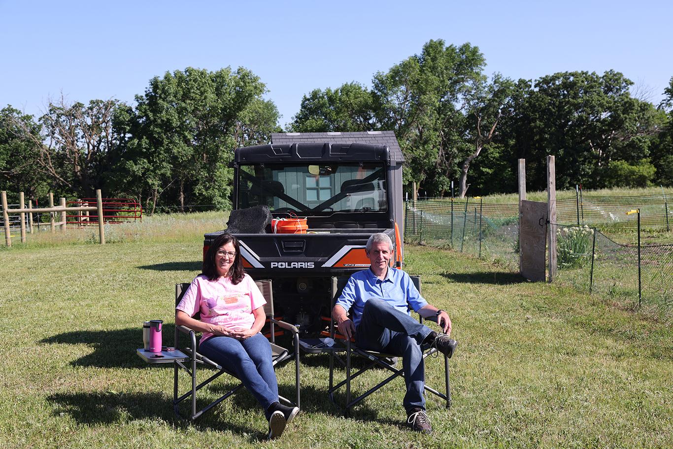 Two people sitting in camping chairs behind a truck