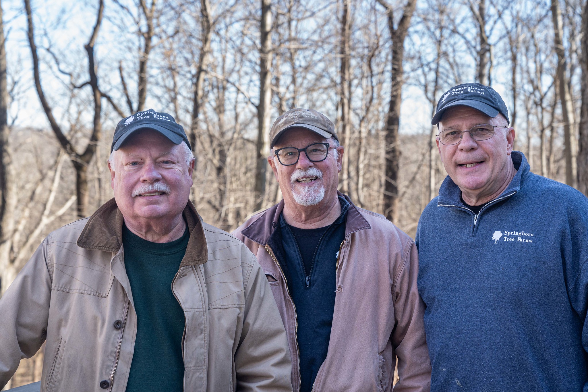 Three people standing in forest