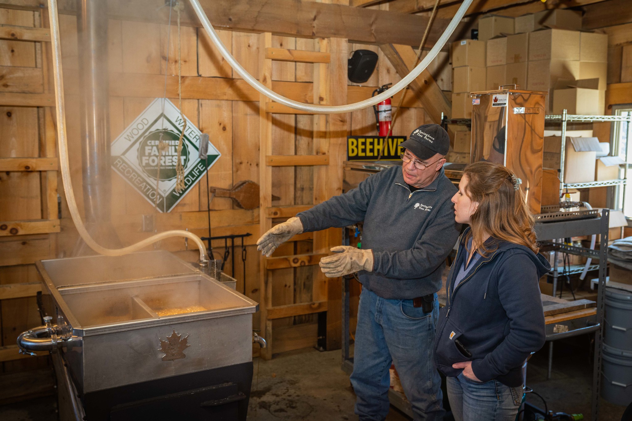 Two people looking at maple syrup vat