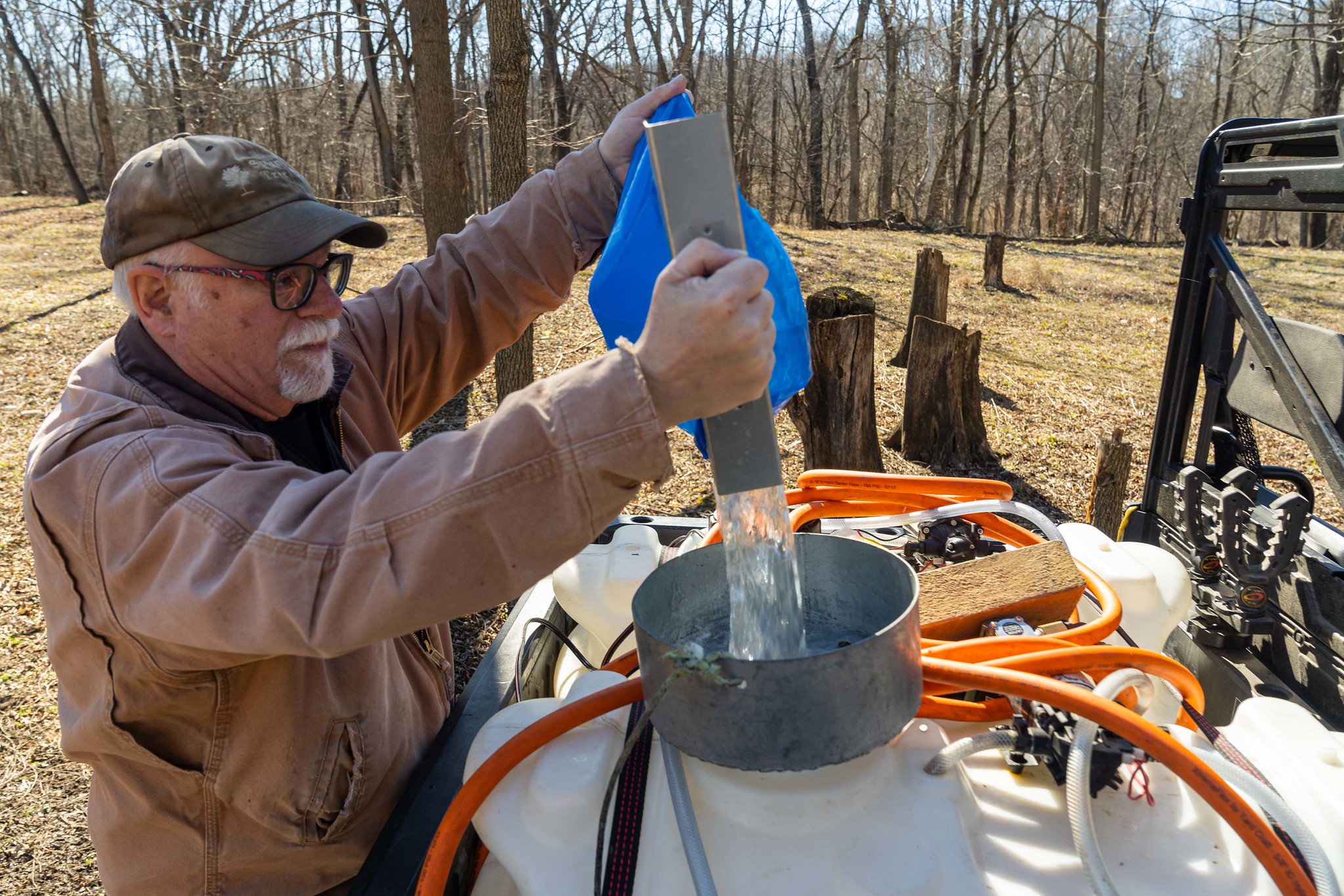 Person pours maple sap into plastic large container
