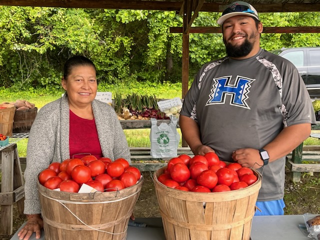 Two people standing behid two baskets of persimmons