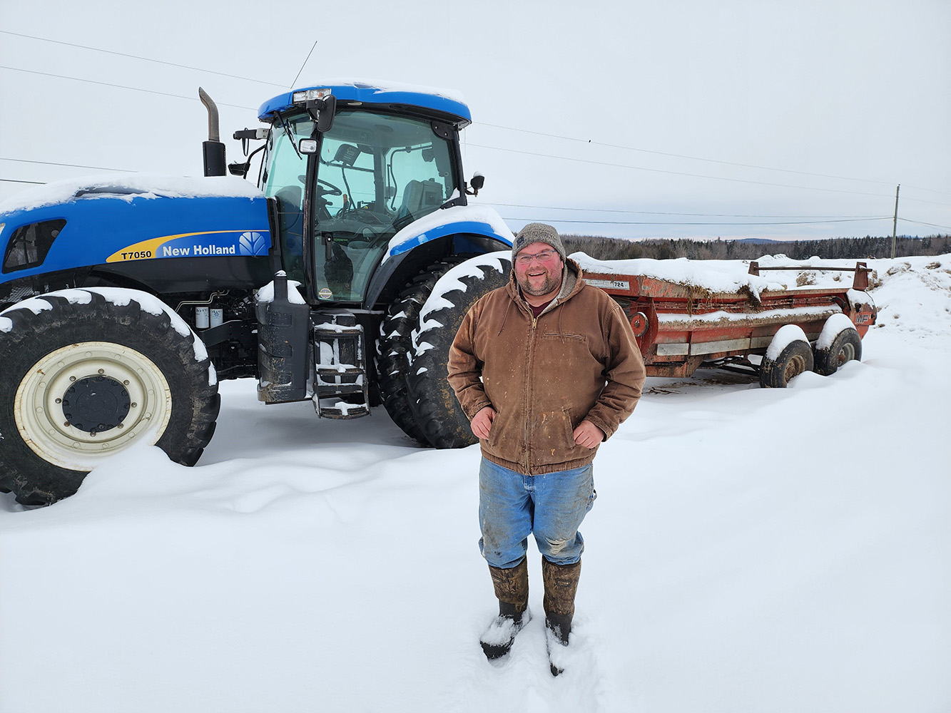 Person standing in snow in from of a green tractor