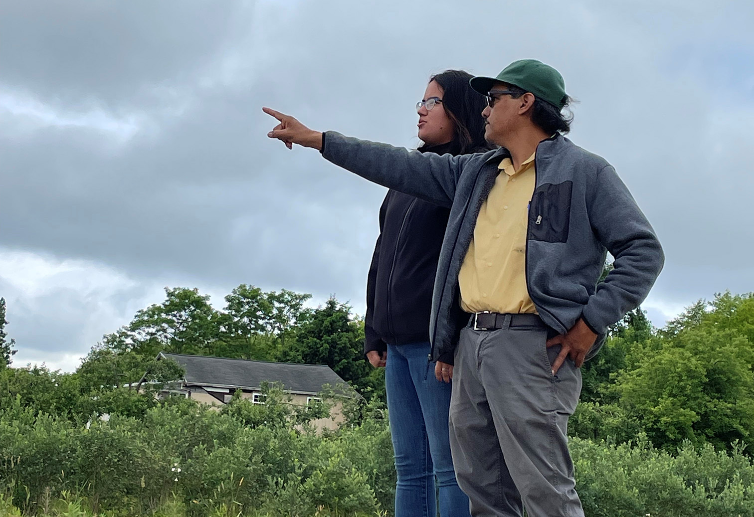 Two people pointing towards horizon