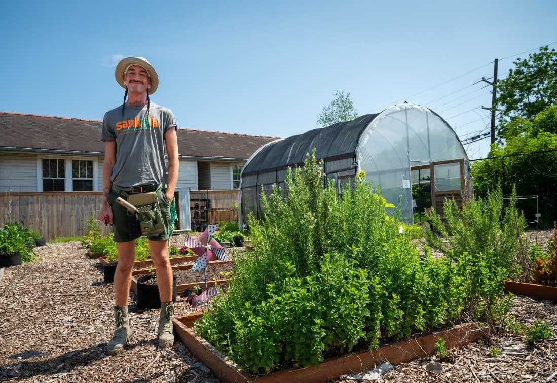 Person standing in garden with a high tunnel in background