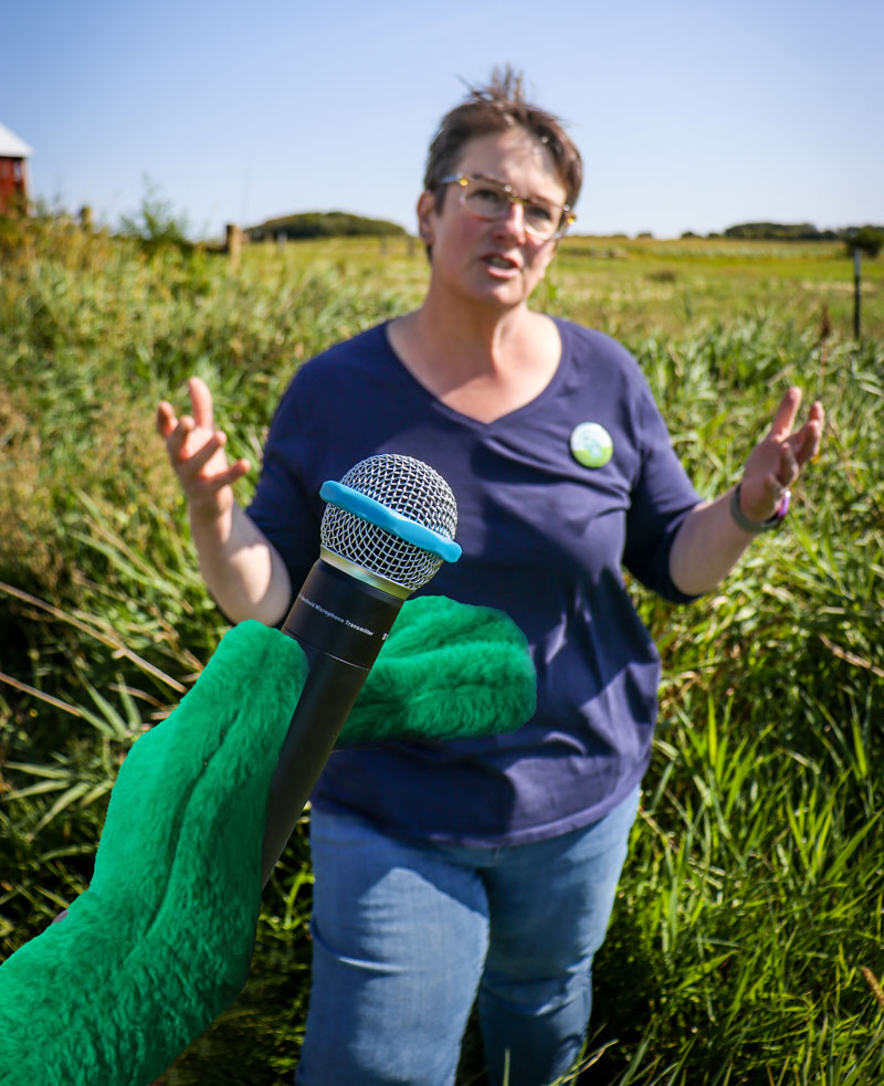 Person standing in pasture with microphone in face.