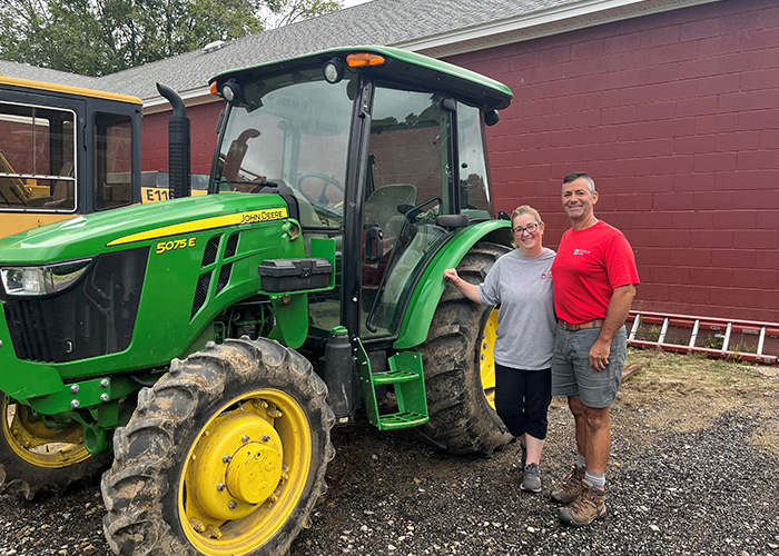 Two people standing in front of a tractor