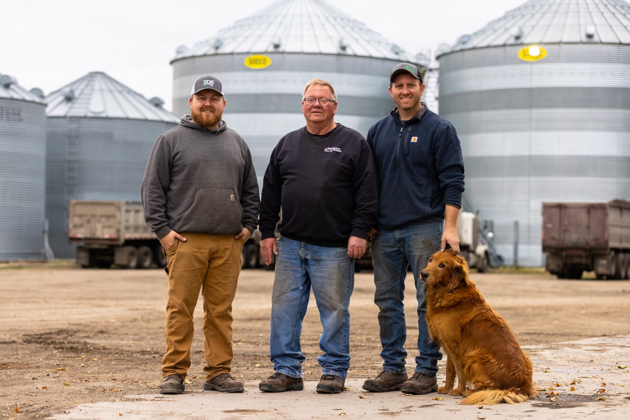 Three people and a dog standing in front of silos