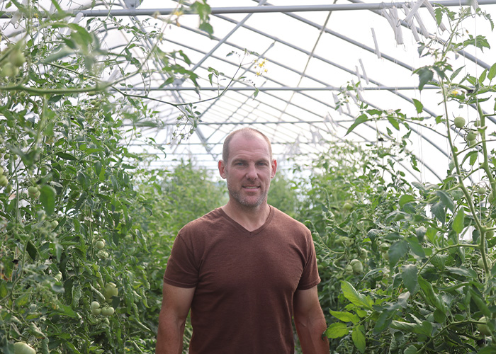 Person standing in green house amongst plants