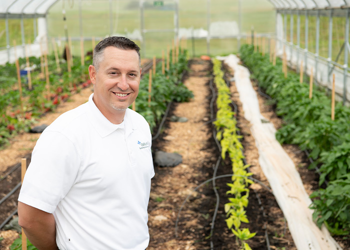 Person standing in front of crops growing in high tunnel