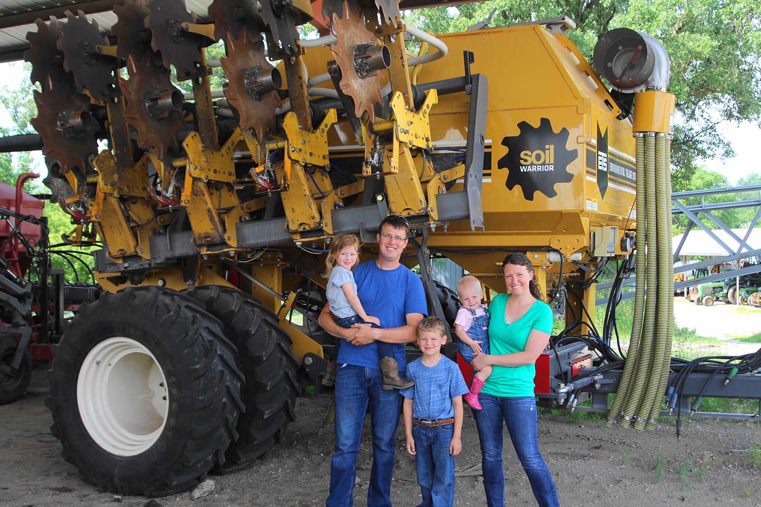 Three people and a dog in front of tilling machine