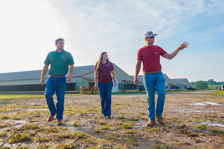 Three people standing in field