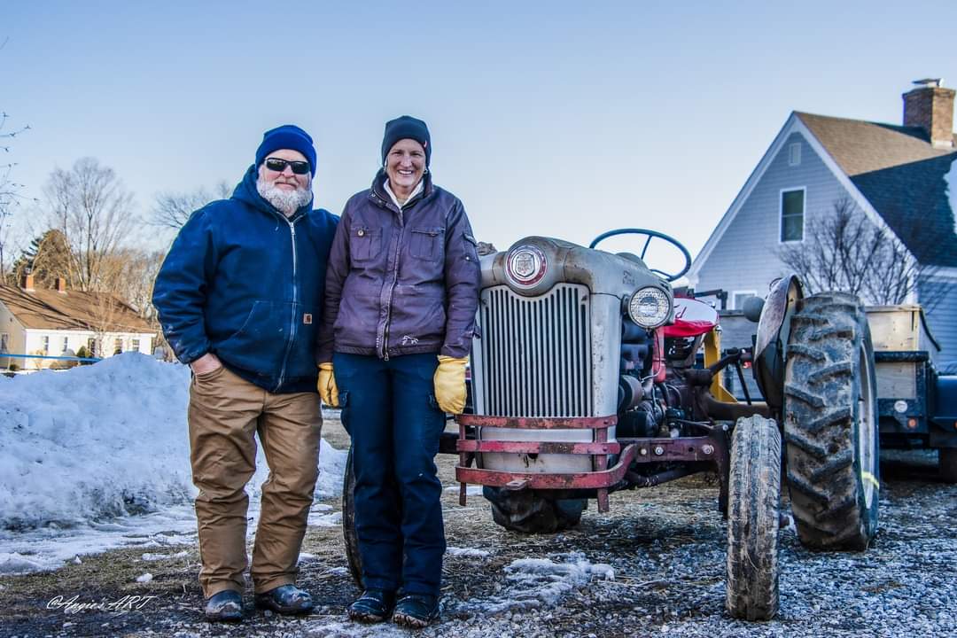 Two people standing in front of a vintage tractor