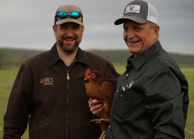 Two people holding a chicken