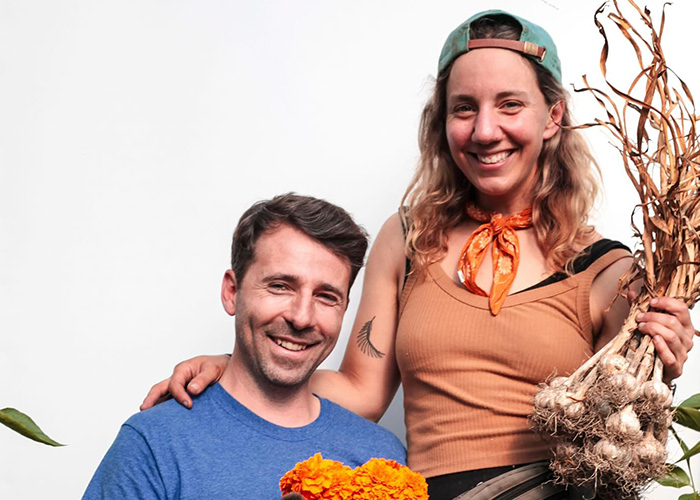 Two people holding freshly picked garlic and flowers