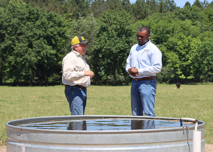 Two people talking near a water trough