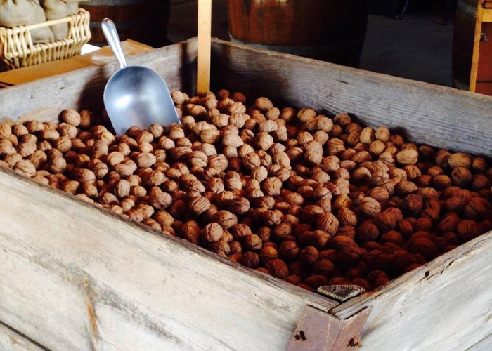 Walnuts in a wooden box with a metal scroop with them