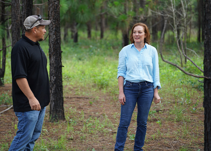 Two people standing in a tree grove