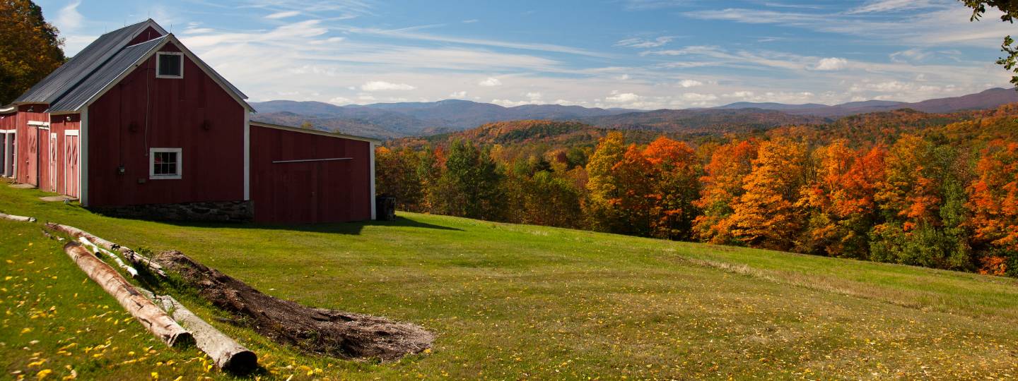 Barn on grass field with fall foliage