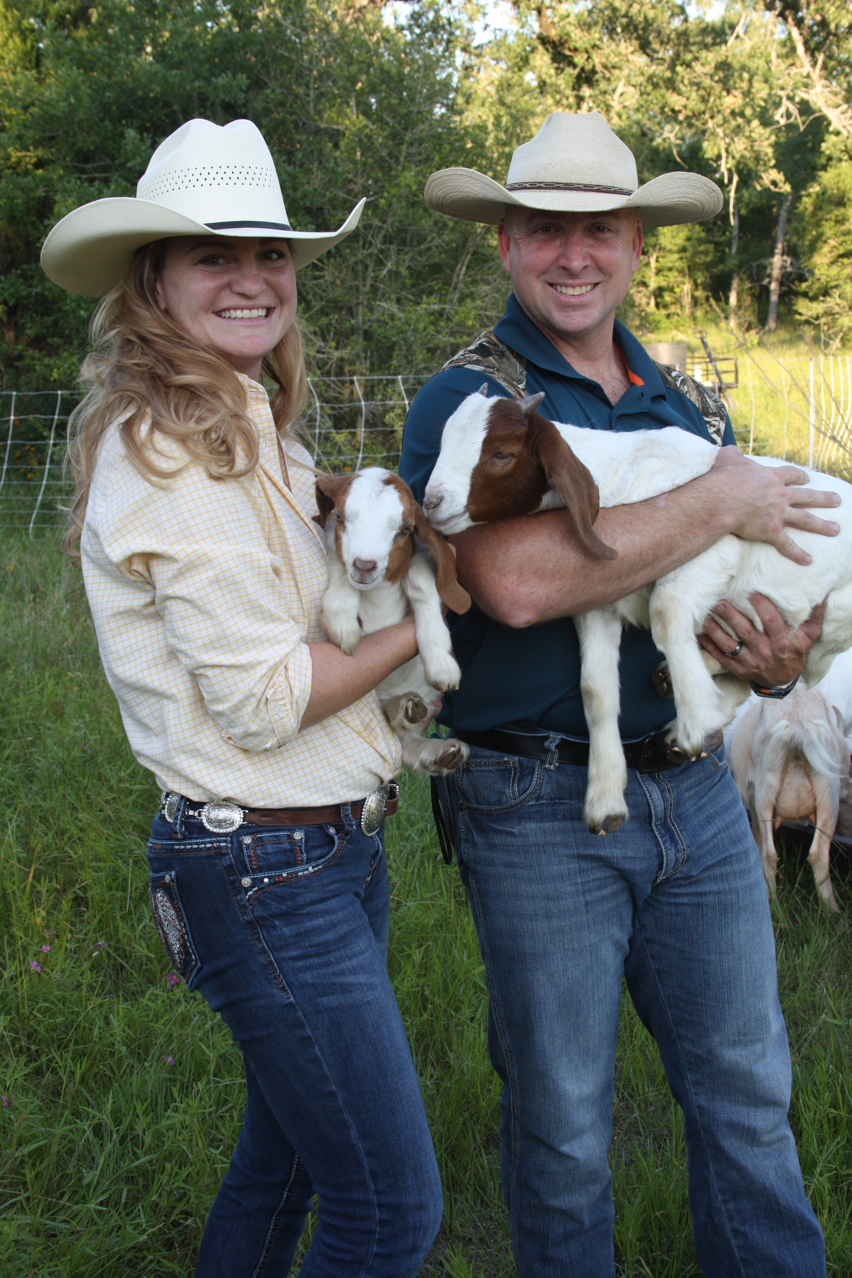 two farmers holding goats