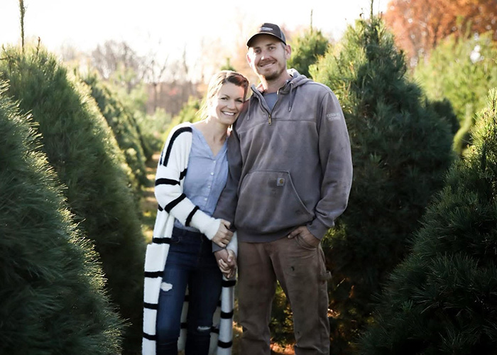 Two people standing in a row of trees